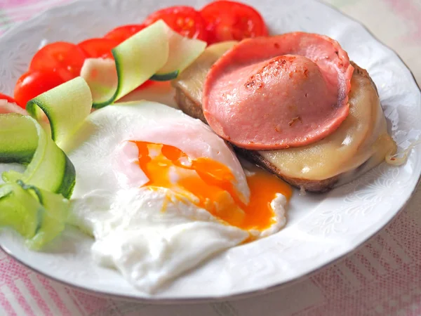 Ready-made Breakfast of eggs with liquid yolk, sausage and cheese sandwich decorated with tomatoes and cucumber slices — Stock Photo, Image