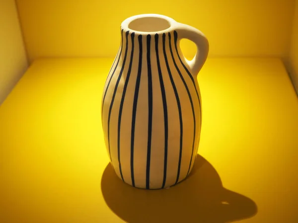 A vase with stripes in a box filled with yellow light — 图库照片