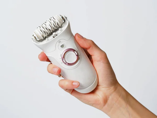 Wanita epilator putih di tangan wanita dengan latar belakang putih. Perangkat penghapusan rambut listrik. Konsep perawatan kulit dan kecantikan perempuan. Wanita menderita . — Stok Foto