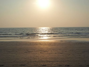 Deniz ve kumsalın arka planında güzel bir gün batımı.