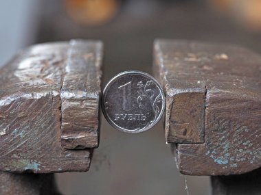 İki taraftan da metal bir mengene tarafından klempe edilmiş bir Rus rublesi. Finansal ve iş sorunları kavramı. Ekonomi sıkışık.