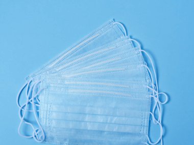 Mavi arka planda cerrahi koruyucu yüz maskeleri var. Virüs ve bakterilere karşı koruma kavramı.