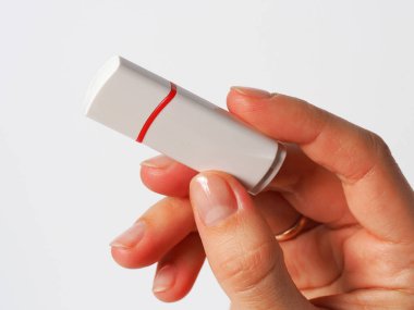 Kızın elinde beyaz bir USB bellek var.