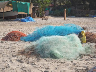 Eski renkli balıkçı ağları kumlu sahilde bir yığın halinde uzanır.