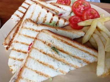 Kızarmış sandviç, yanında sebze ve patates kızartması.