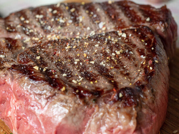 A large piece of juicy fresh beef sprinkled with spices. Stripes-rare, the juice from the meat. Close-up, front view