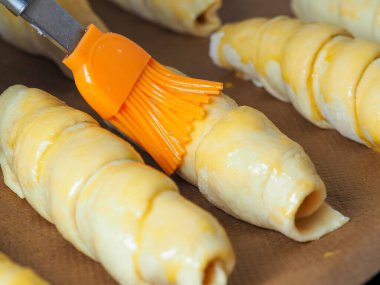 Hamurun içindeki sosisler pişirmeye hazırdır. Yumurta sarısını fırçala. Kapatın. Evde yemek pişirmek.