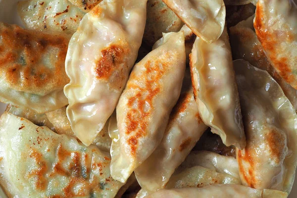 Dumplings are fried in a pan. Asian dish with a variety of fillings. Fried Gyoza. Close up, top view