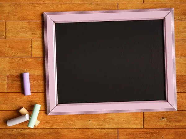 Chalkboard and colorful chalks over wooden table. 3D illustration — Stock Photo, Image