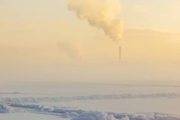 Niebla de invierno sobre el río congelado y la tubería de la fábrica . Fotos De Stock Sin Royalties Gratis