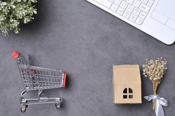 shopping online concept. small red trolley and white keyboard and empty post it for text on the black table background. Home delivery products for shopping online. Online shopping delivery.