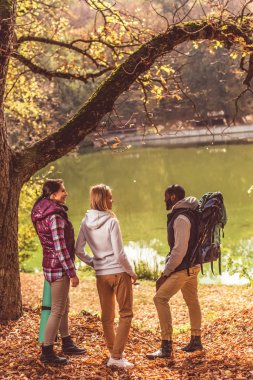 Genç backpackers nehir kenarında yürüyüş