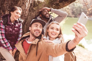 Young people taking selfie in forest clipart