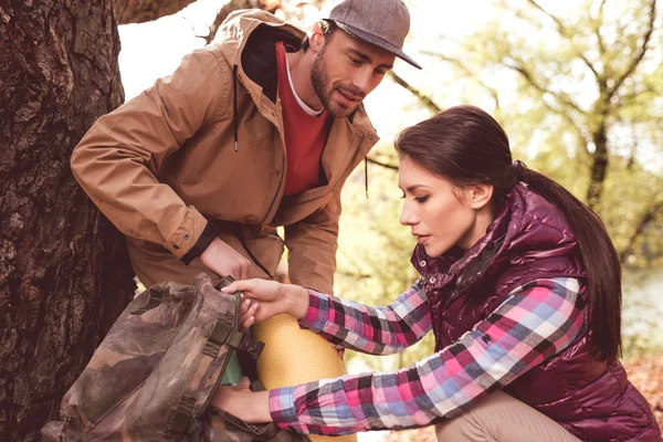 Mann sieht Frau beim Rucksackpacken an — Stockfoto