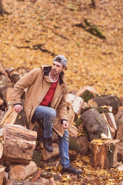 Junger Mann sitzt auf trockenen Stümpfen — Stockfoto