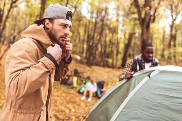 Мужчины ставят палатку в осеннем лесу
 