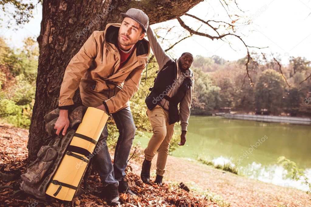 Men backpackers standing near river