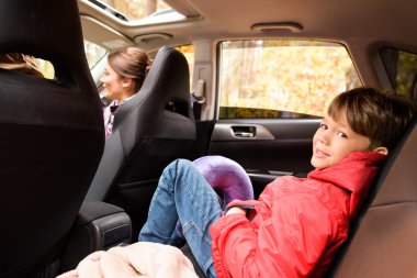 Smiling boy in back seat of car clipart