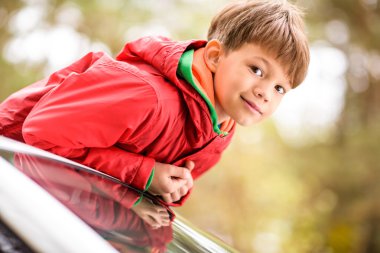 Cute little boy standing in car  clipart