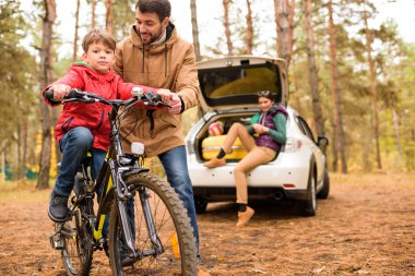 Father teaching son to ride bicycle clipart