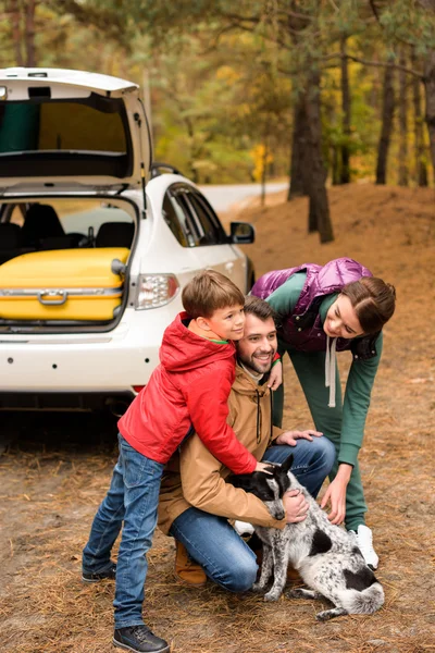 Glückliche Familie spielt mit Hund im Wald — Stockfoto