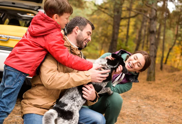 Familia feliz jugando con el perro en el bosque — Foto de Stock