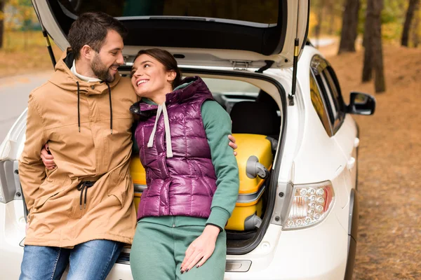 Smiling couple sitting in car trunk — Stock Photo, Image