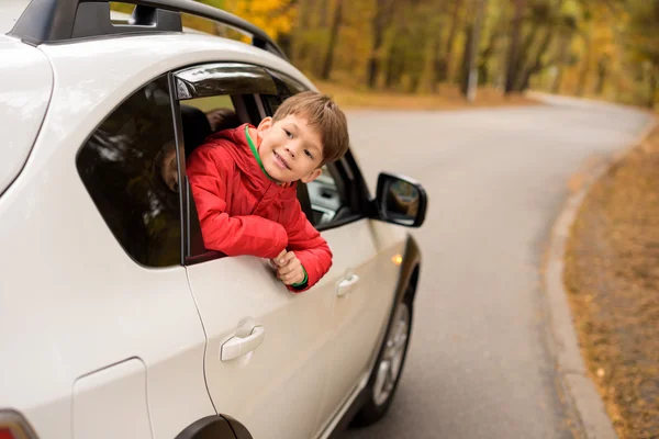 Усміхнений хлопчик дивиться крізь вікно машини — стокове фото