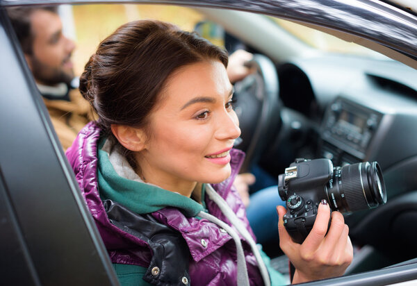 Smiling woman holding camera in car
