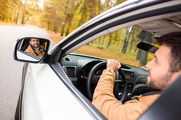 Șofer zâmbitor reflectat în oglinda mașinii — Fotografie, imagine de stoc