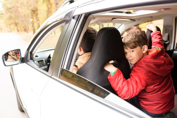 Garçon souriant sur le siège arrière de la voiture — Photo