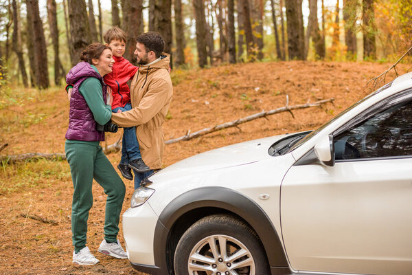Счастливая семья возле машины в лесу
