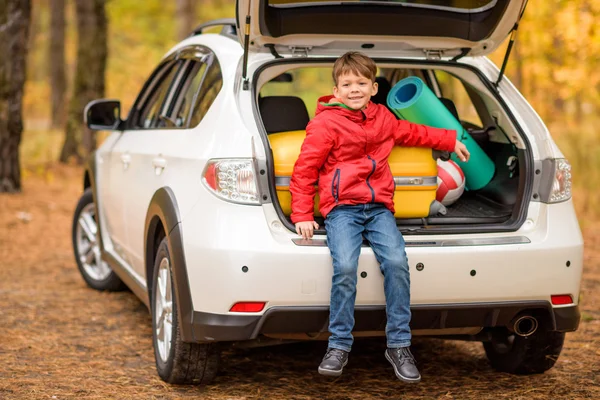 Sorrindo menino sentado no porta-malas do carro — Fotografia de Stock