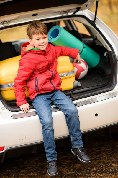Lachende jongen zitten in auto kofferbak — Stockfoto