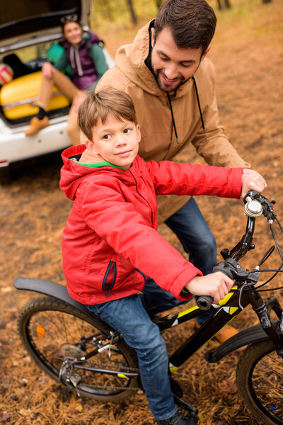 Отец учит сына ездить на велосипеде
