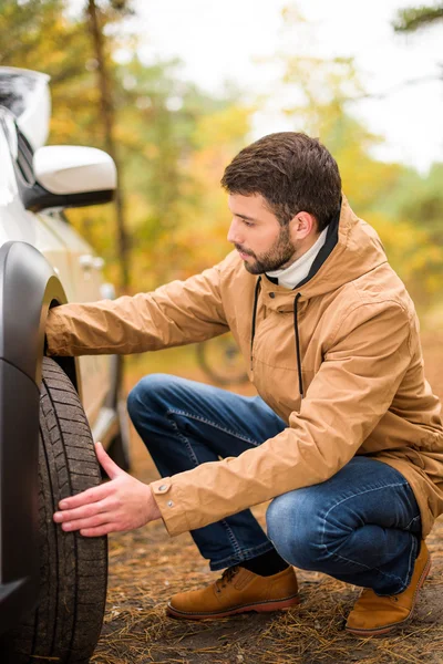 Homme vérifiant pneu voiture — Photo
