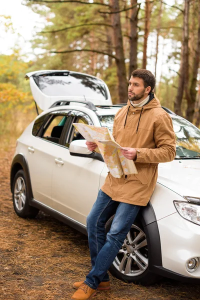Man holding map and leaning on car — Stock Photo, Image