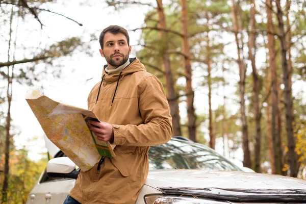 Mann hält Karte und lehnt sich an Auto — Stockfoto