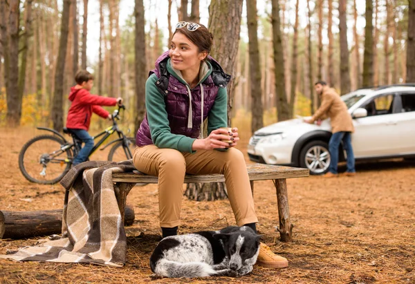 Smiling woman with hot drink in forest — Stock Photo, Image