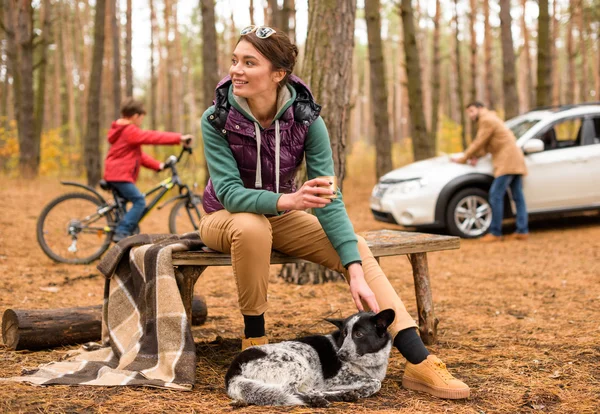 Mujer sonriente con bebida caliente en el bosque — Foto de Stock