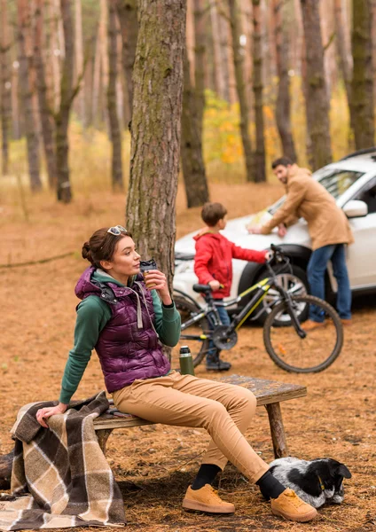 Femeia zâmbitoare cu băutură fierbinte în pădure — Fotografie, imagine de stoc