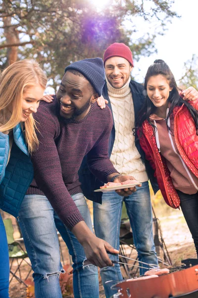 Smiling friends preparing barbecue in park — Stock Photo, Image