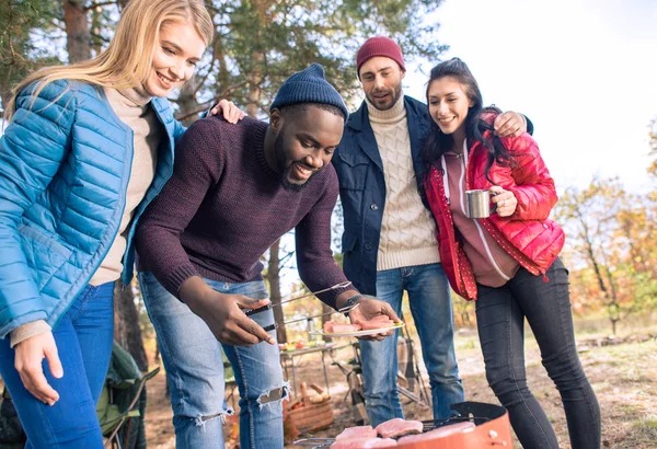 Smiling friends preparing barbecue in park — Stock Photo, Image