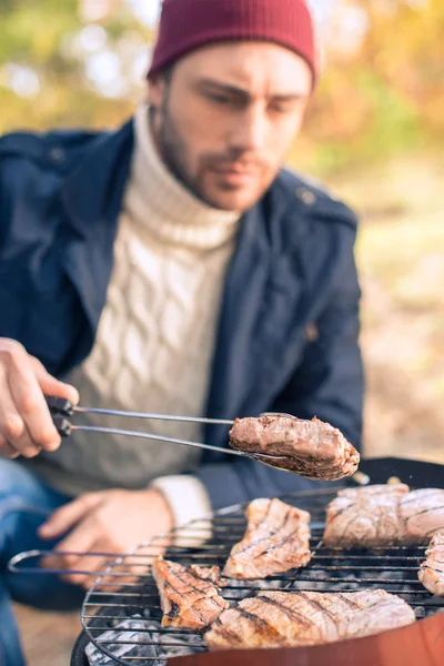 Человек готовит мясо на угольном гриле — стоковое фото