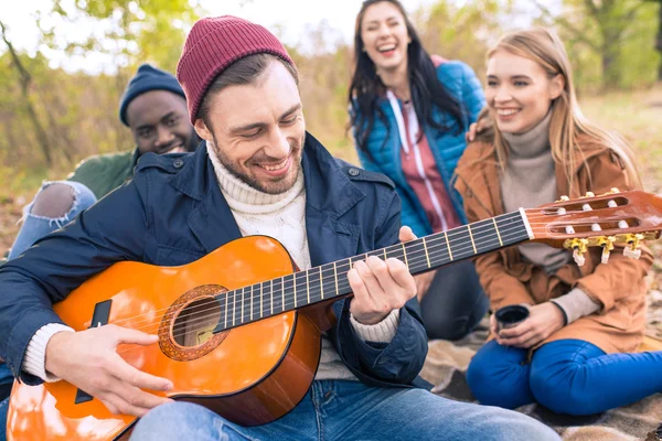 Friends enjoying guitar in autumn park — Stock Photo, Image