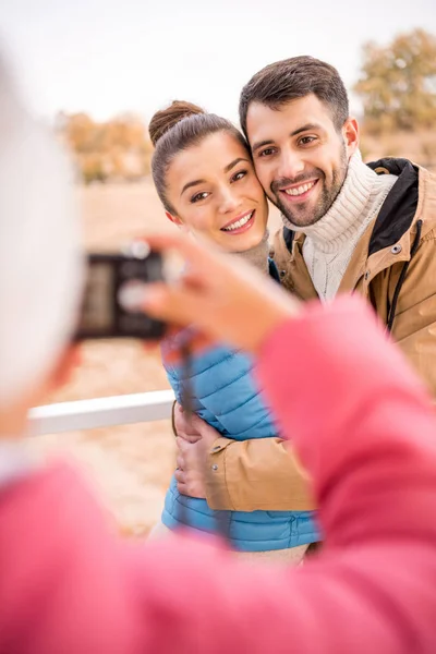 Chica fotografiando hermosa pareja sonriente — Foto de Stock
