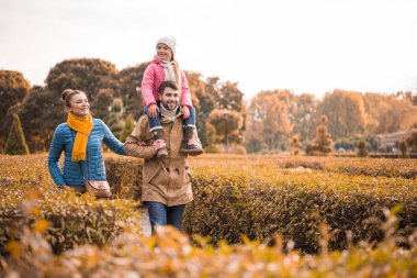 Mutlu bir aile parkta yürüyor.