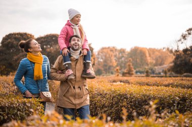 Mutlu bir aile parkta yürüyor.
