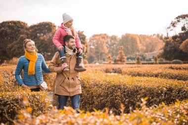 Mutlu bir aile parkta yürüyor.