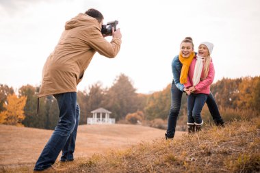 Man photographing happy mother and daughter clipart